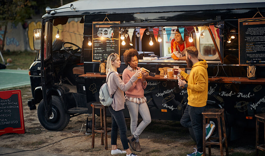 Group of young people socializing while eating outside in front of a food truck in Castle Rock, CO