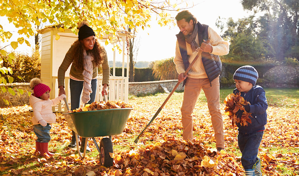 Family raking leaves together in the fall for home maintenance prep for winter in Colorado.